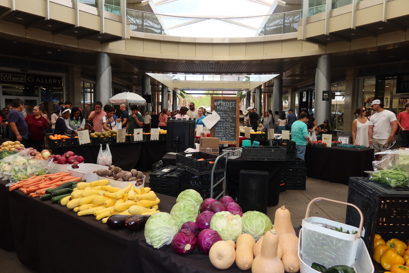 Fresh produce on display at the Downtown Summerlin Farmers Market — carrots, cabbages, squash, peppers, and more under the Pavilion