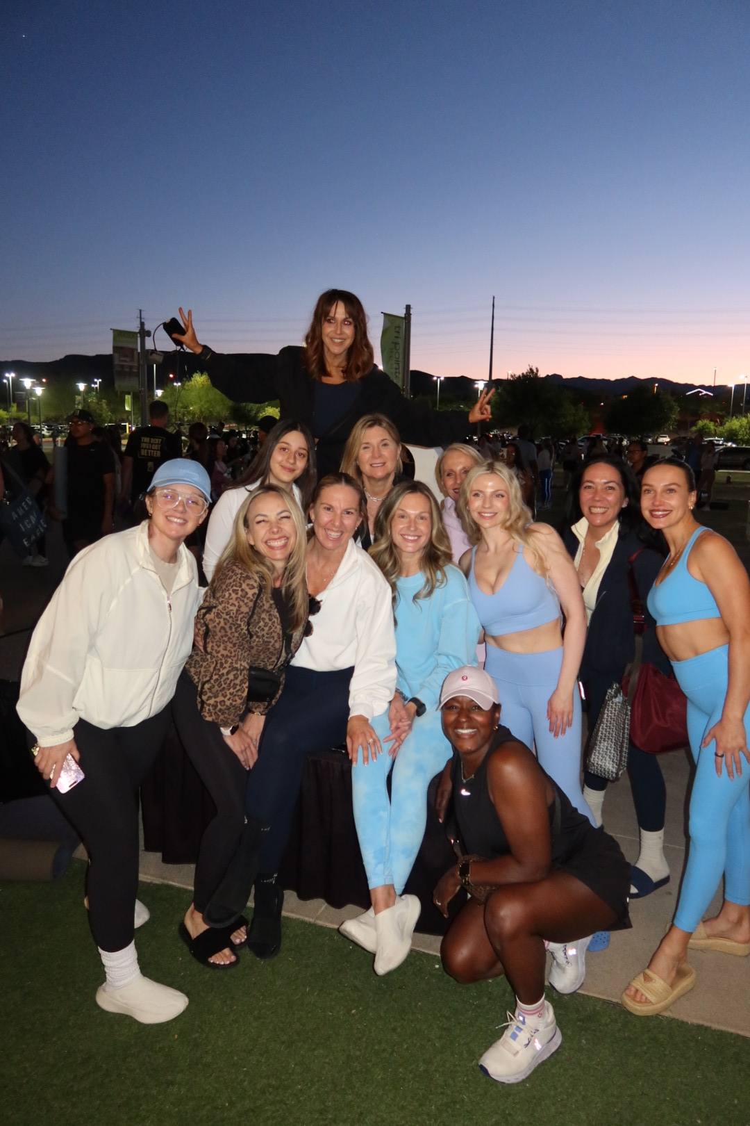 Group photo of Jackie Harris and supporters in athletic wear at Fitness on the Lawn Downtown Summerlin at dusk
