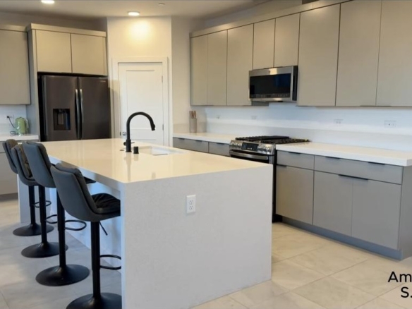 Modern kitchen with a large white island and gray cabinetry in a modern Summerlin home in Redpoint