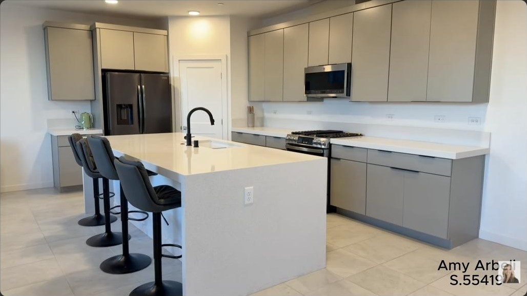 Modern kitchen with a large white island and gray cabinetry in a modern Summerlin home in Redpoint