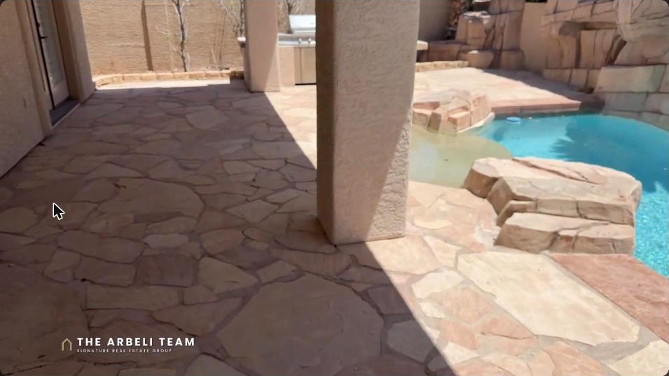 Long lap pool with a waterfall and rock features on an 11,000 square foot Summerlin estate lot in The Vistas