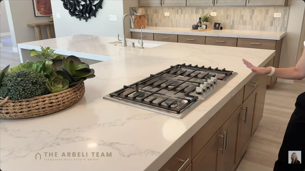 Gourmet chef kitchen with a large waterfall quartz island and gas cooktop in a Summerlin West home