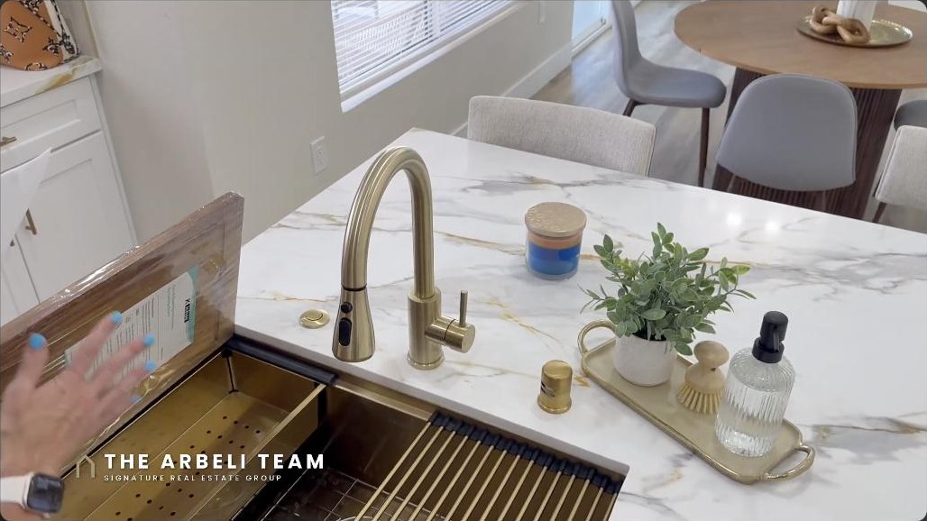 Renovated kitchen with waterfall quartz island and gold sink and faucet in a Sun City Summerlin Weston