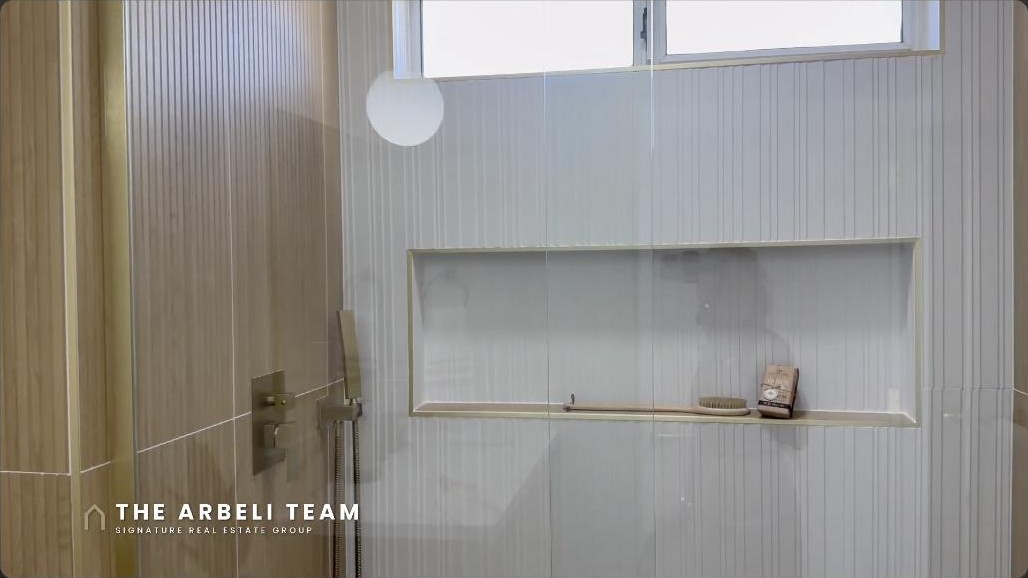 Primary bathroom walk-in shower with wood-look tile and gold fixtures