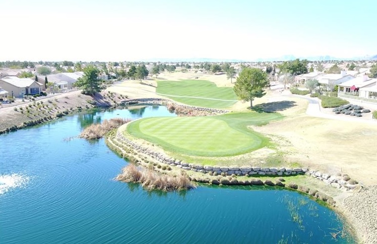 Aerial view of a golf course green and water hazard surrounded by single-story homes in Sun City Summerlin, Las Vegas