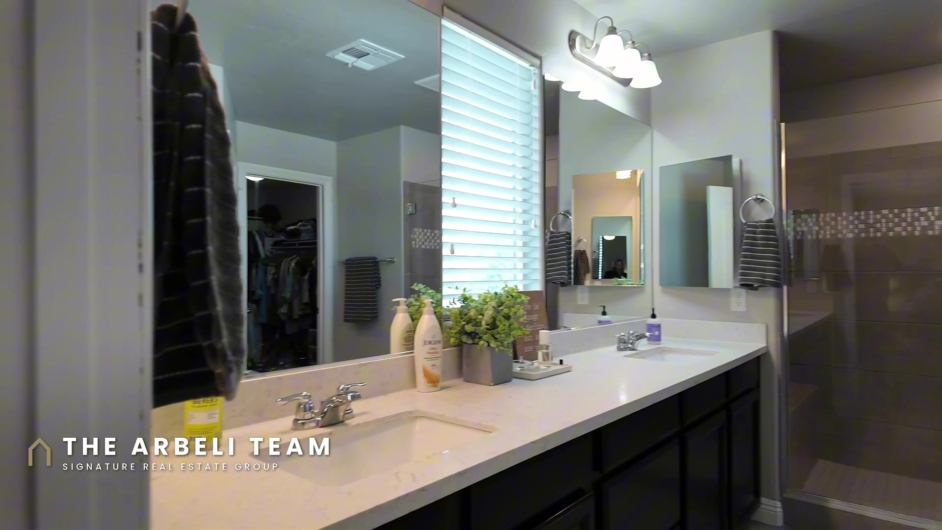 Primary bathroom at 7204 Site Street with dual vanities and a glass walk-in shower