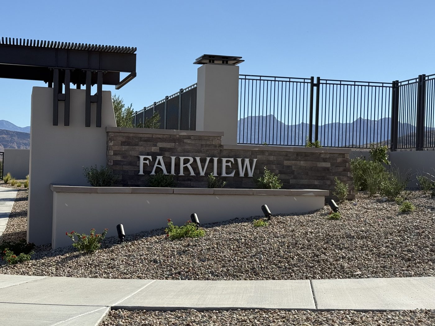Stone and stucco entrance monument reading Fairview at the gated Lennar single story community in Grand Park, Summerlin West, Las Vegas, Nevada, with the mountains behind it