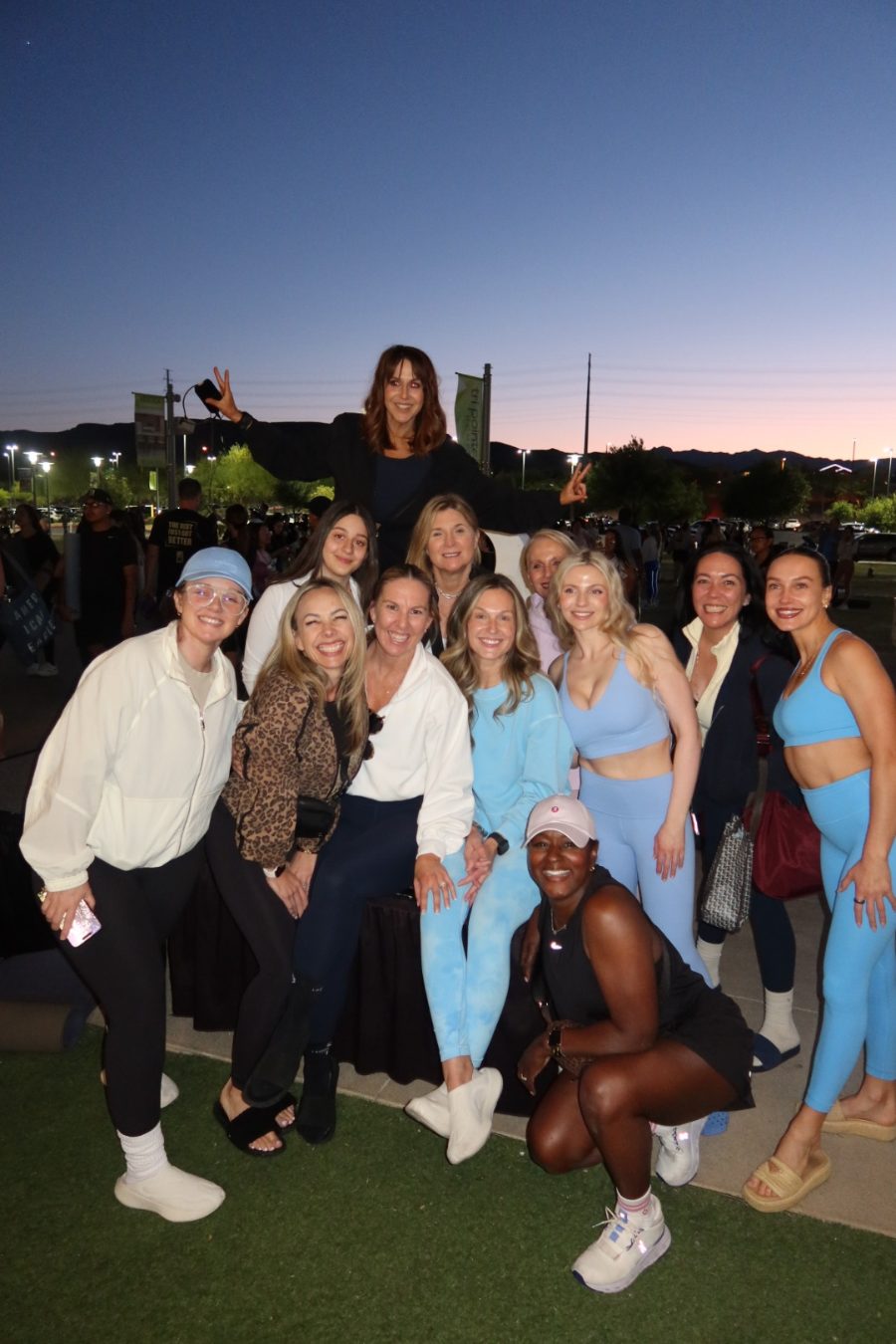 Group photo of Jackie Harris and supporters in athletic wear at Fitness on the Lawn Downtown Summerlin at dusk