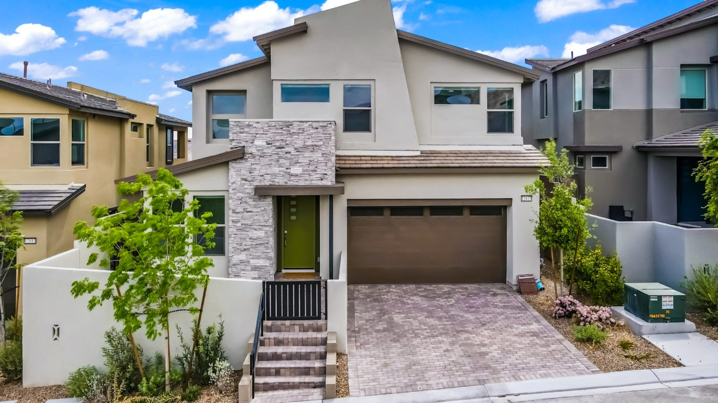 Front exterior of a two story home for sale in Redpoint, Summerlin West, with stone veneer, a green front door and a two car garage
