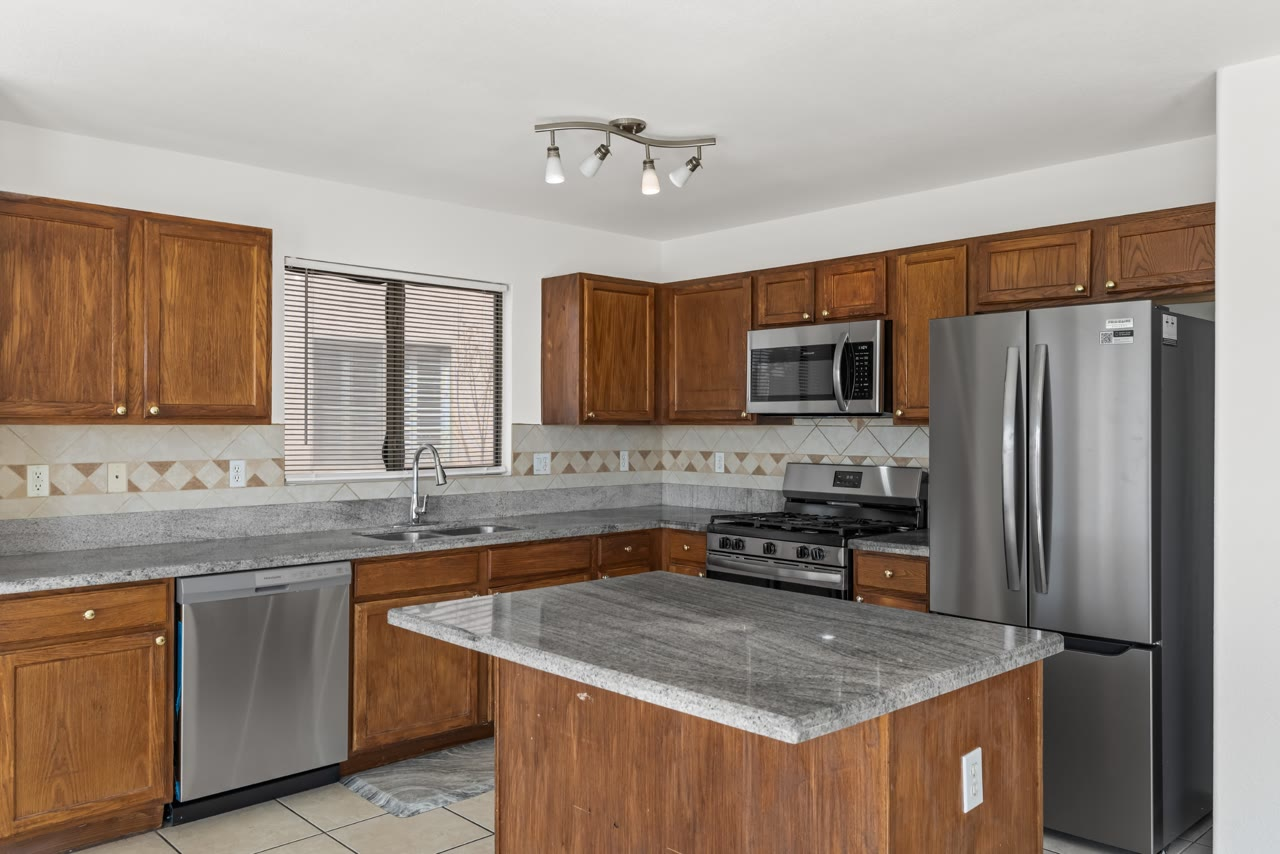 Kitchen with granite counters, oak cabinets, an island and brand new Frigidaire appliances at 4655 Gracemont Avenue, Las Vegas 89139