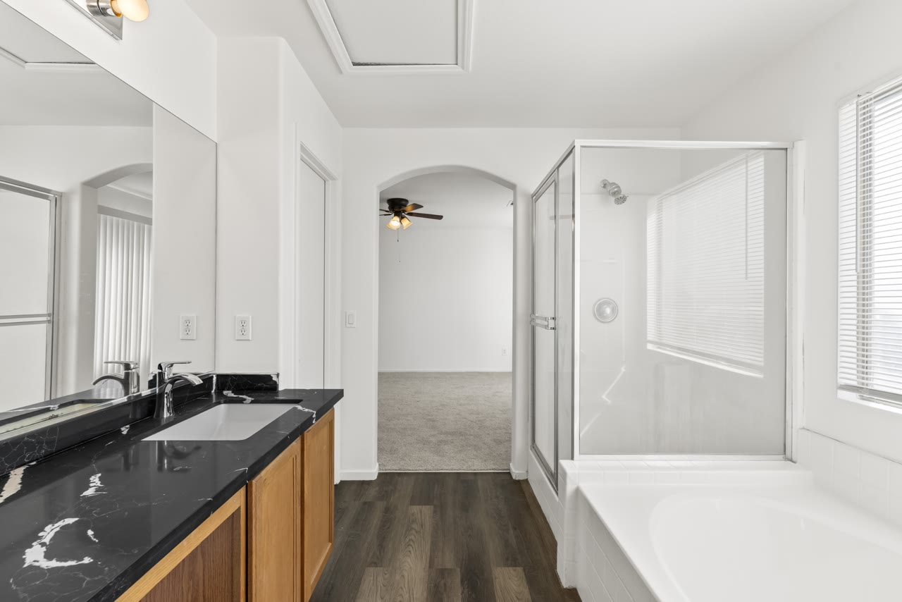 Primary bathroom with a soaking tub, glass shower and plank floors at 4655 Gracemont Avenue, southwest Las Vegas