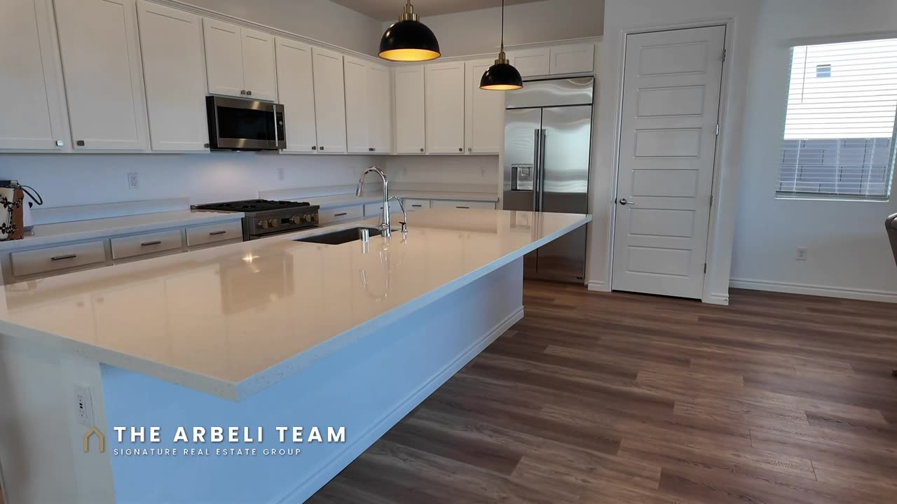 Kitchen with a long island, three pendants and Monogram appliances in a Heritage at Stonebridge 55+ home in Summerlin