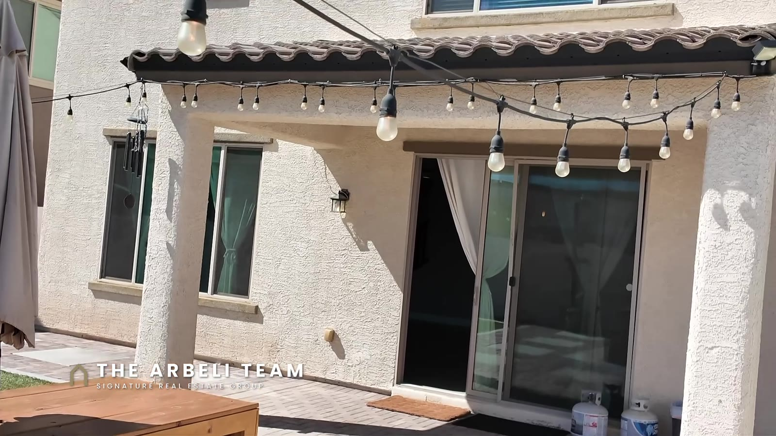 Covered patio with bistro lights and pavers in the finished backyard at 7204 Site Street, Las Vegas 89113