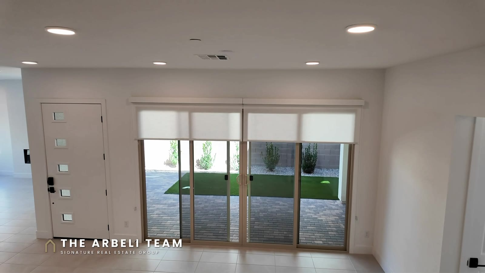 Dining area with double sliders opening to a landscaped courtyard with artificial turf at Aberdeen Collection II, Summerlin West